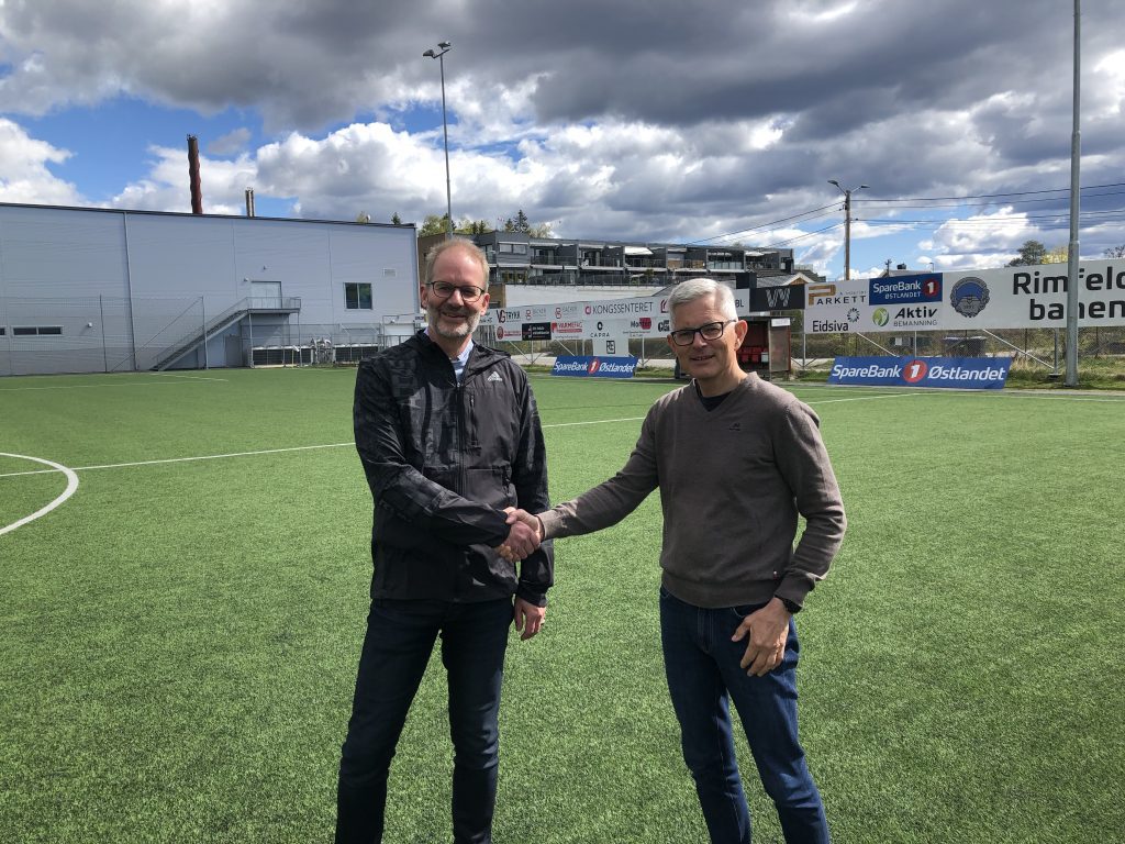 bildet viser to menn utepå fotballbanen som tar hverandre i hendene